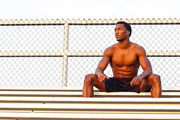 Serious Black athlete siting on bleachers