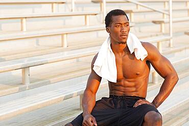 Black athlete sitting on bleachers