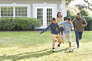 Family playing soccer in backyard