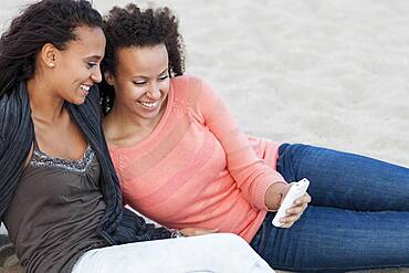 Close up of women using cell phone on beach