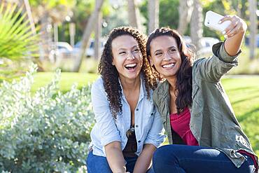 Smiling women taking selfie in park