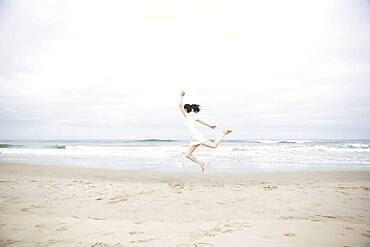 Woman jumping for joy on beach