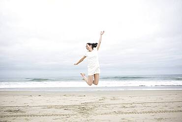 Woman jumping for joy on beach