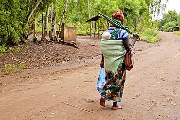 Mother carrying baby with traditional wrap on dirt road