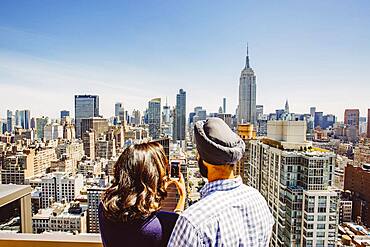 Indian couple taking cell phone photograph of New York cityscape, New York, United States