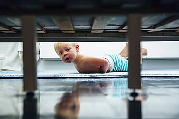 Mixed race boy peering under bed