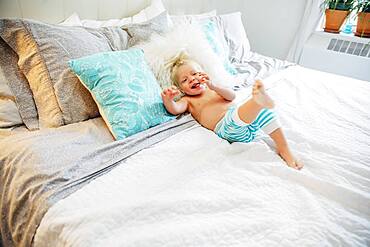 Mixed race boy playing on bed