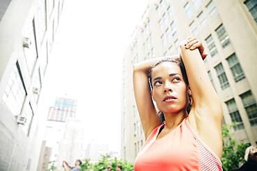 Mixed race athlete stretching in city