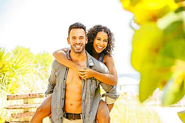 Man carrying girlfriend piggyback on beach