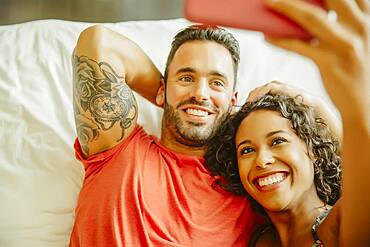 Couple taking selfie with cell phone on bed