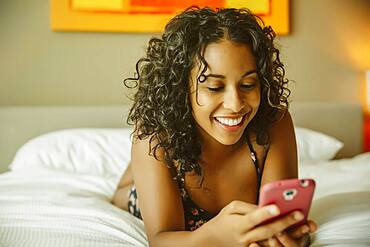 Close up of woman using cell phone on hotel bed