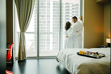 Couple hugging in bathrobes in hotel room