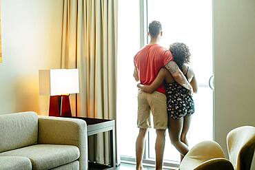 Couple hugging and looking out hotel window