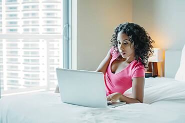 Woman using laptop on hotel bed