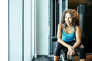 Woman sitting on exercise machine in gymnasium