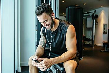 Man listening to earbuds in gymnasium