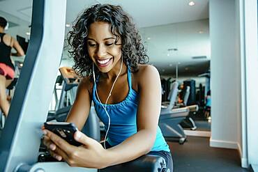 Woman listening to earbuds in gymnasium