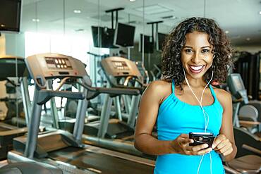 Woman listening to earbuds in gymnasium