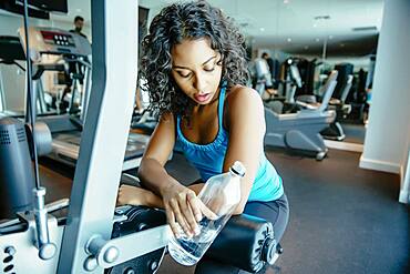 Woman resting on exercise machine in gymnasium