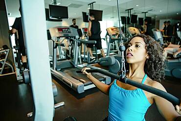 Woman using exercise machine in gymnasium