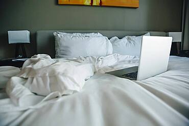 Laptop on empty bed