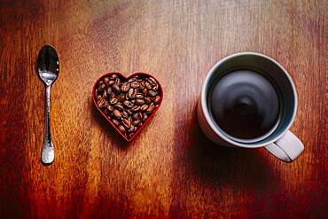 Spoon, beans and cup of coffee on counter