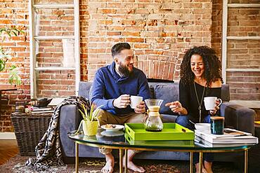 Couple drinking coffee on sofa in living room