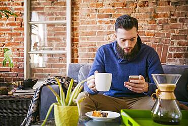 Caucasian man drinking coffee on sofa in living room