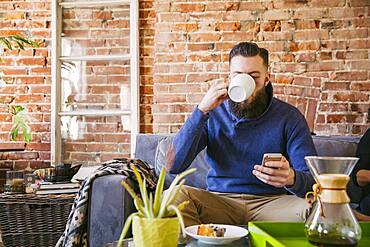 Caucasian man drinking coffee on sofa in living room