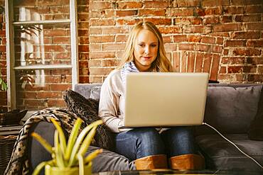 Caucasian woman using laptop on sofa