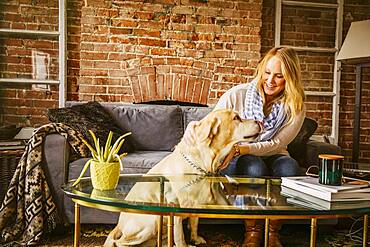 Caucasian woman petting dog in living room