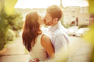 Caucasian couple kissing on sidewalk