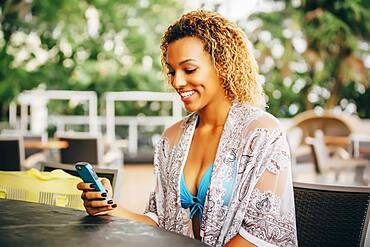 Mixed race teenager using cell phone at table