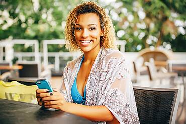 Mixed race teenager using cell phone at table