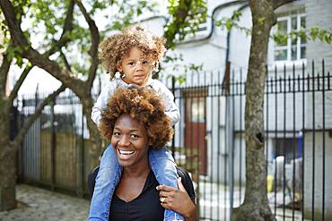 Mother carrying daughter on shoulders outdoors