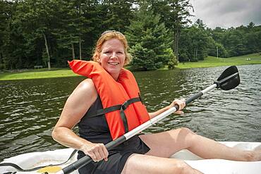 Caucasian woman rowing canoe in lake