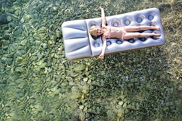 Caucasian girl floating on raft in lake