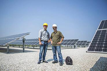 Caucasian technicians standing near solar panels