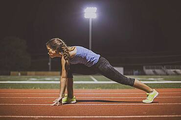 Mixed race runner in starting position on sports field