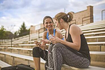 Women using cell phones on bleachers