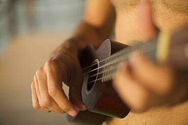 Mixed race man playing ukulele on beach