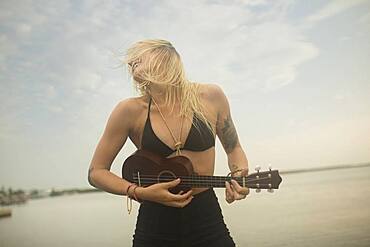 Caucasian woman playing ukulele on beach