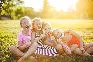 Girls eating flavored ice in sunny field