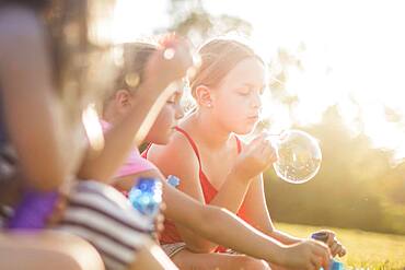 Girls blowing bubbles in grass field