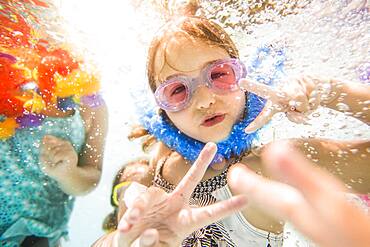 Caucasian children swimming underwater in swimming pool