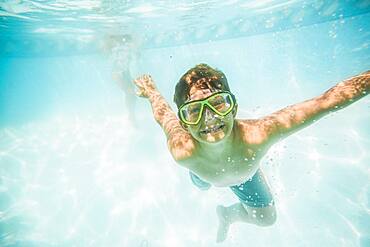 Caucasian boy swimming underwater in swimming pool