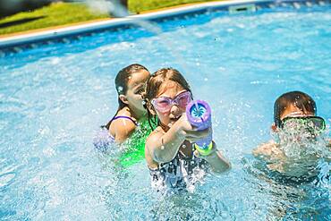 Children playing with squirt gun in swimming pool