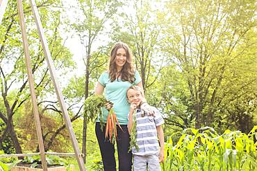 Caucasian mother and son holding carrots in garden