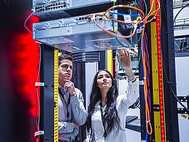 Technicians examining computer in server room