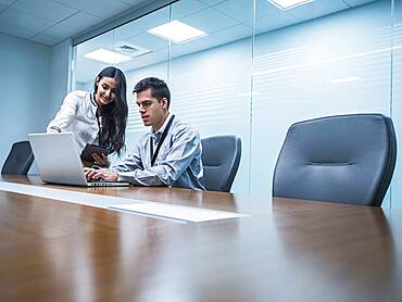 Business people using laptop in conference room